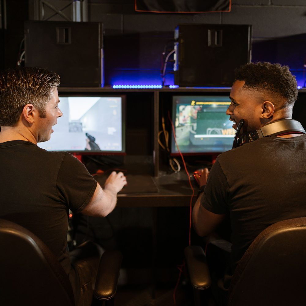 A snug two-seat corner with two gaming PCs and a shared side table for drinks